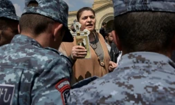 Une Arménienne brandit une croix devant des policiers anti-émeutes lors de manifestations antigouvernementales dimanche 22 avril à Erevan.