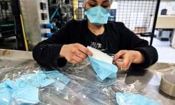 Une employée emballe des masques de protection resppiratoire sur une ligne d'assemblage de l'usine Valmy, le 28 février 2020 à Mably, dans la Loire