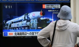 Une passante regarde le journal télévisé annonçant le tir d'un missile nord-coréen, le 13 avril 2023 à Tokyo