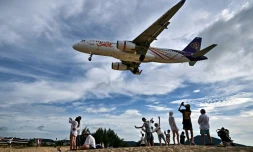 Des touristes prennent la pose sur la plage de Mai Khao, sur l'ßle thaïlandaise de Phuket, juste à cÎté de l'aéroport international qui doit s'agrandir face à la hausse programmée du nombre de passagers dans les années à venir, le 18 novembre 2023