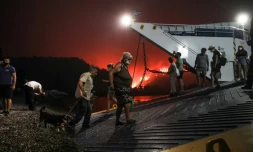 Des habitants embarquent sur un ferry pour évacuer le village côtier de Limni (Grèce), encerclé par un feu de forêt, le 6 août 2021