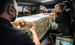 Une proche endeuillée accompagne le cercueil contenant la dépouille d'une victime de l'incendie d'un bar, dans un fourgon funéraire, le 14 juillet 2026 à l'hôpital général de la police de Bangkok, en Thaïlande
