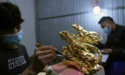 Un artisan recouvre de feuilles d'or une figurine de tigre dans un atelier Ă HanoĂŻ, au Vietnam, le 19 janvier 2022