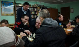 Viktor Jouravski (debout), directeur de la pension neuropsychiatrique pour hommes de Novo-Bilytsky regarde des patients jouer aux échecs, le 12 mars 2022 à Kiev