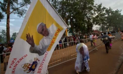 Un homme tient une bannière à l'effigie du pape François à Namugongo, en Ouganda, le 28 novembre 2015