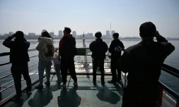 Des touristes observent la ville nord-coréenne de Sinuiju (arriÚre-plan) depuis un bateau touristique sur le fleuve Yalu, dans la ville frontaliÚre de Dandong, dans le nord-est de la Chine, le 26 mars 2026