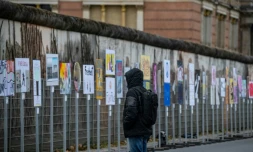 Un homme regarde des pancartes installées le long de l'ancien tracé du Mur de Berlin vendredi 8 novembre, en vue des célébrations des 35 ans de la chute du Mur de Berlin, intervenue le 9 novembre 1989