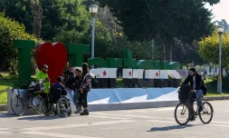 Des Syriens à Tartous, dans l'ouest de la Syrie, devant une enseigne peinte aux nouvelles couleurs du pays, le 17 décembre 2024