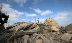 Un Palestinien au sommet des décombres d'un bâtiment touché par une frappe israélienne dans le camp de réfugiés de Bureij, dans le centre de la bande de Gaza, le 10 juillet 2025