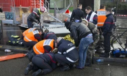 Les pompiers administrent les premiers soins à un couple à Paris, blessé par la chute d'un panneau publicitaire en raisons de fortes rafales de vent, le 8 février 2016