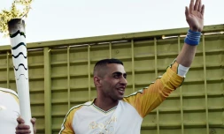 Le réfugié syrien Ibrahim al-Hussein, nageur amputé de guerre, porte la flamme olympique dans le camp de réfugiés d'Eleonas, à Athènes, le 26 avril 2016