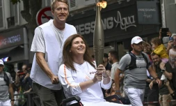 La photographe de l'Agence France-Presse (AFP) Christina Assi portant la flamme olympique (c) et le journaliste vidéo Dylan Collins (g) à Vincennes, le 21 juillet 2024