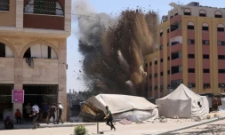 Des Palestiniens se précipitent pour se mettre à l'abri après qu'une frappe israélienne a touché un immeuble à proximité à Jabalia, dans le nord de la bande de Gaza, le 20 août 2025

