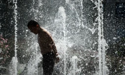 Un enfant se rafraßchit dans des jeux d'eau au parc André Citroën à Paris le 23 juillet 2019