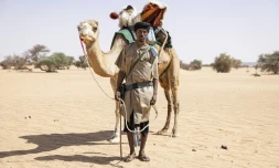 Sidnq, un membre de l'unité du Groupement nomade de la Garde nationale mauritanienne, pose pour un portrait à côté de son dromadaire dans la région de Hodh Ech Chargui (Mauritanie), le 7 avril 2025