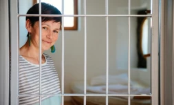 Tanja Lipovec, responsable de l'hôtel auberge Celica à Ljubljana, pose derrière le barreaux d'une ancienne cellule transformée en chambre d'hôtel, le 29 juillet 2016