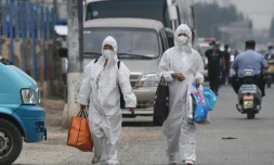 Deux Chinoises en combinaison intégrale de protection passent prÚs du marché de Xinfadi, fermé aprÚs l'apparition de nouveaux cas de coronavirus, le 13 juin 2020 à Pékin