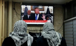 Deux palestiniens regardent le président américain Donald Trump reconnaître officielement Jérusalem comme capitale de l'Etat d'Israël le 6 décembre
