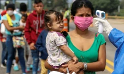 Des employés du ministère de la Santé prennent la température de Vénézuéliens retournant au pays depuis la Colombie, le 4 avril 2020 sur le pont international Simon Bolivar, à Cucuta