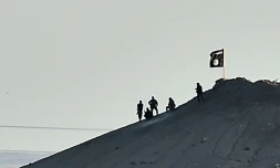 Un drapeau et des hommes groupe Etat islamique (EI)à Ain al-Arab en Syrie, le 6 octobre 2014