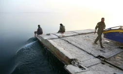 Des combattants arabes syriens attendent des civils fuyant les combats, au bord du lac artificiel Assad à Tabqa (nord) et qui sert actuellement de corridor fluvial, le 29 avril 2017
