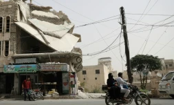 Une homme roule sur une motocyclette devant un bâtiment endommagé dans la ville de Binnish, dans le nord de la province d'Idleb en Syrie, le 15 octobre 2018