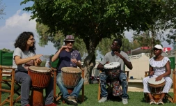 Le Gambien Ibrahim Kamara (2e d), demandeur d'asile, joue du djembé avec ses élèves lors d'une foire de la diversité à Nicosie, le 14 mai 2023 à Chypre
