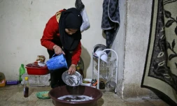 Cédra al-Hassan, une déplacée syrienne de Deir Ezzor, fait la vaisselle dans une bassine posée à même le sol dans une cave de la ville d'Al-Bab (nord de la Syrie), où elle habite aux côtés d'une dizaines d'autres déplacés, le 7 décembre 2018