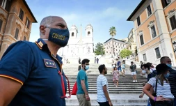 Un policier italien patrouille et surveille que les passants portent le masque sur la Place d'Espagne à Rome le 17 août 2020 pendant l'épidémie de Covid-19
