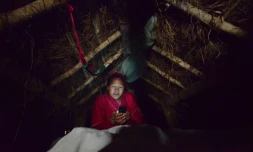 La Népalaise Pabitra Giri regarde son smartphone dans une hutte lors de la "chhaupadi", l'exil imposé aux femmes à chaque cycle menstruel, le 3 février 2017 à Surkhet, à l'ouest de Katmandou