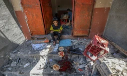 Des enfants palestiniens récupèrent du pain dans une boulangerie détruite par des frappes israéliennes dans le camp de réfugiés de Nousseirat, dans le centre de la bande de Gaza, le 8 mai 2025