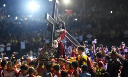 Une foule de catholiques accompagne la statue de Jésus de Nazareth portant la croix du Calvaire, lors de la procession annuelle du "Nazaréen Noir" à Manille le 9 janvier 2019