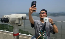 Un touriste prend un selfie avec une tasse Starbucks devant la Corée du Nord depuis une plate-forme d'observation sud-coréenne située à l'Écoparc de la Paix d'Aegibong, à Gimpo, le 1er juillet 2026 
