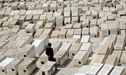 Un homme se recueille sur une tombe dans le cimetiÚre juif du Mont des Oliviers, en face de la Vieille ville de Jérusalem, le 9 septembre 2018