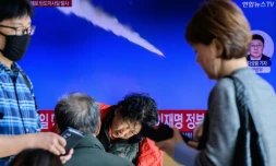 Des passants regardent une télévision diffusant un journal télévisé avec des images d'archives d'un essai de missile nord-coréen, dans une gare de Séoul, le 7 novembre 2025