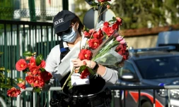 Une policiÚre ramasse des fleurs apportées en hommage à Stéphanie Monfermé, le 26 avril 2021 devant l'h?'tel de police de Rambouillet
