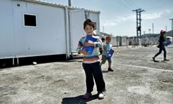 Un jeune garçon devant un conteneur reconverti en salle de classe, le 24 juin 2016 dans le camp de réfugiés de Skaramangs (sud de Athènes)