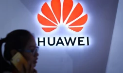 Photo d'illustration d'une femme passant devant le logo de Huawei à Pékin le 8 juillet 2018