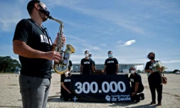 Un membre du personnel de Santé joue du saxo devant un cercueil pour dénoncer la mort de 300.000 personnes au Brésil victimes sud Covid-19 à Brasilia le 25 mars 2021