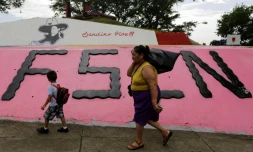 Une femme et un enfant marche devant un monument à la mémoire du révolutionnaire Augusto C. Sandino, à Managua, le 17 juillet 2018