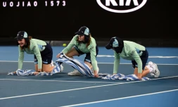 Des ramasseuses de balles épongent un court lors de l'Open d'Australie, le 20 janvier 2020 à Melbourne