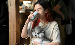 La jeune toiletteuse pour animaux Lucine Mo boit son café dans une tasse jetable isotherme dotée d'un QR code, dans un café de Hong Kong, le 2 novembre 2023