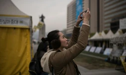 Une femme prend en photo une manifestation anti-gouvernementale, dans le centre de Séoul, le 3 novembre 2016