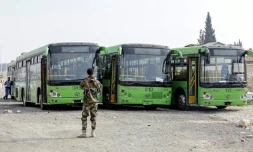 Photo de bus stationnés au point de passage de Wafidine, entre la capitale syrienne Damas, et l'enclave rebelle dans la Ghouta orientale, dans l'attente d'évacuations, le 13 mars 2018