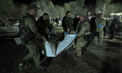 Des policiers ukrainiens portent le corps d'une victime tuée dans une frappe russe, le 5 octobre 2023 à Groza (Ukraine)