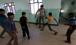 Des garçons jouent au foot dans leur école avec un soldat des forces irakiennes, le 12 novembre 2016, dans le village de Jarif, à environ 45 kilomètres au sud de Mossoul