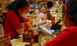 Une vendeuse rend la monnaie à un client dans un magasin alimentaire de Tokyo, le 29 juillet 2021