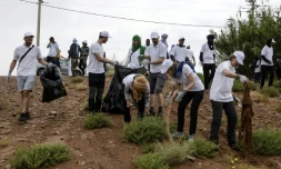 Des bénévoles ramassent des déchets lors d'une campagne de nettoyage de M'Hamid El Ghizlane, aux portes du désert, dans le sud Maroc, le 12 avril 2025
