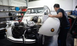 Dans les ateliers du Mehari Club de Cassis (Bouches-du-Rhône), un mécano extrait le moteur thermique d'une ancienne 2CV pour en installer un autre électrique, le 9 juillet 2020