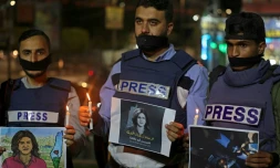 Des journalistes tenant des bougies à la main et des posters de la journaliste palestinienne tuée Shireen Abu Akleh, lors d'une cérémonie à Rafah dans la bande de Gaza, le 11 mai 2022 
